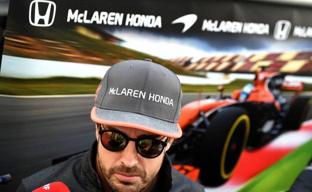 Fernando ALonso, delante de un carte de la escudería.