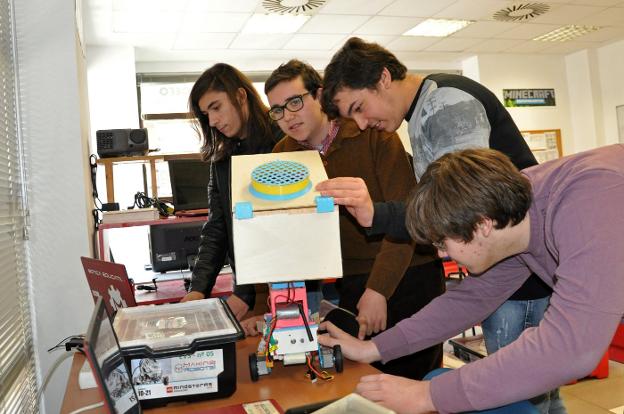 Los cuatro jóvenes examinan el robot ganador en la Roborave Ibérica. :: e. d./