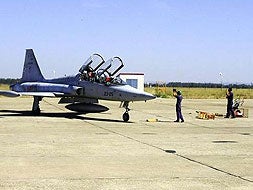 Un F-5 llega a la pista después del vuelo. Abajo le espera su equipo de mecánicos para comprobar.|E,P./