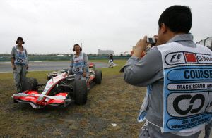 EL TROFEO. Trabajadores del Circuito de Shanghai se fotografían junto al coche de Lewis Hamilton. / REUTERS/