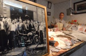 Manuel Macías muestra una foto de Óscar Alonso con los pescaderos de los años cincuenta posando junto a sus cajas de madera en la Plaza Alta. / C. MORENO/
