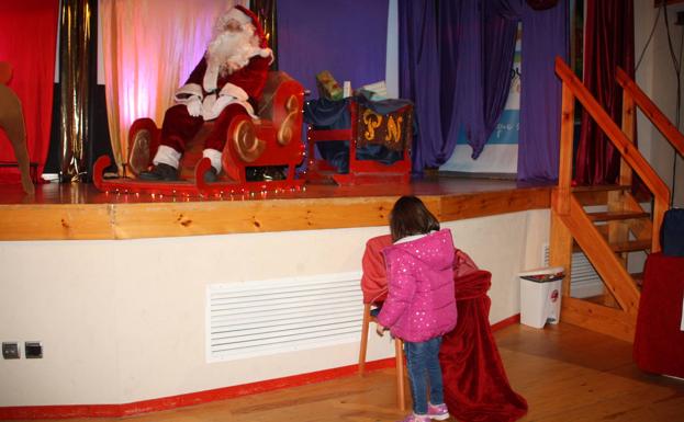 Una pequeña entregando su carta a Papá Noel. 