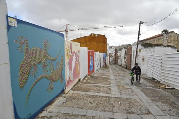 Un hombre sube la calle San Lorenzo acarreando una bici delante de los nuevos murales. / J. V. ARNELAS