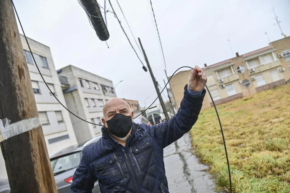 Ramón Prieto sujeta uno de los cables caídos en suelo de su calle. / JOSÉ VICENTE ARNELAS
