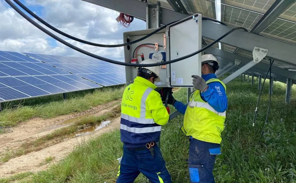 Dos operarios manipulan una de las placas fotovoltaicas en construcción. /