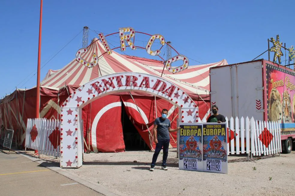 Dos trabajadores del circo colocan carteles anunciadores de la función. / SOL GÓMEZ