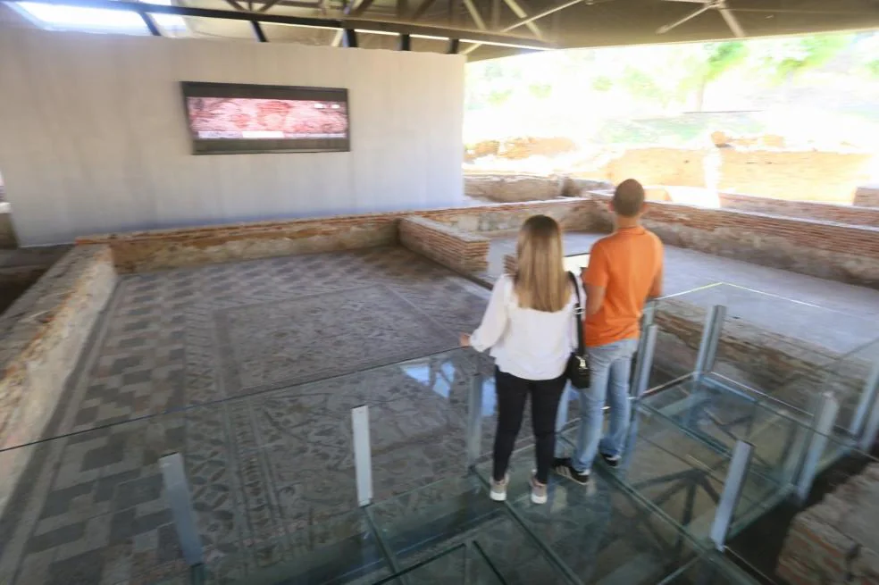 Dos visitantes sobre el pavimento de mosaicos de la Casa del Anfiteatro. / J. M. ROMERO