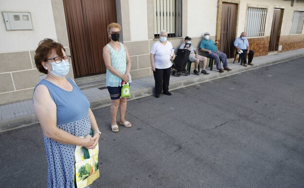 Seis vecinos de Santiago del Campo ya vacunados esperando para entrar en la pequeña tienda del pueblo, con mascarillas y guardando las distancias./a. MÉNDEZ