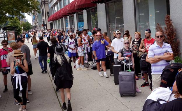 Centenares de asistentes al festival de música Lollapalooza esperaban este viernes a hacerse el control sanitario para entrar en su hotel en Chicago./AFP