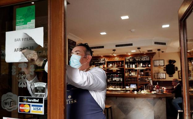 Un hostelero retira un cartel con las limitaciones de aforo en Pamplona./EFE