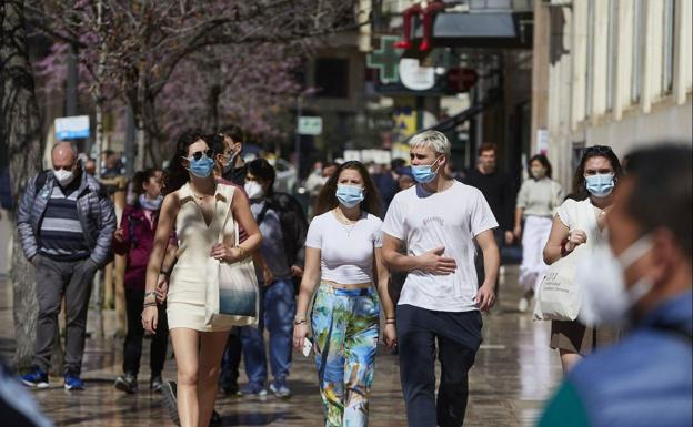 Perdsonas pasean por una calle de Valencia portando mascarillas. /Iván Arlandis