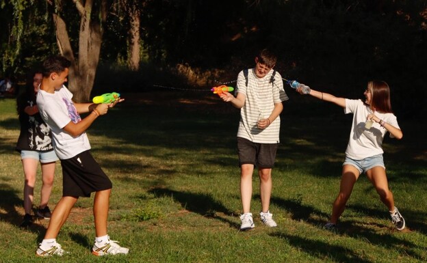 Jóvenes refrescándose con pistolas de agua en un parque de Mérida. /ÁNGEL BLANCO