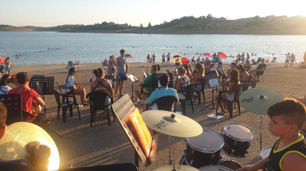La banda de Puebla de Alcocer toca en la playa de Orellana la Sierra. / S. G.