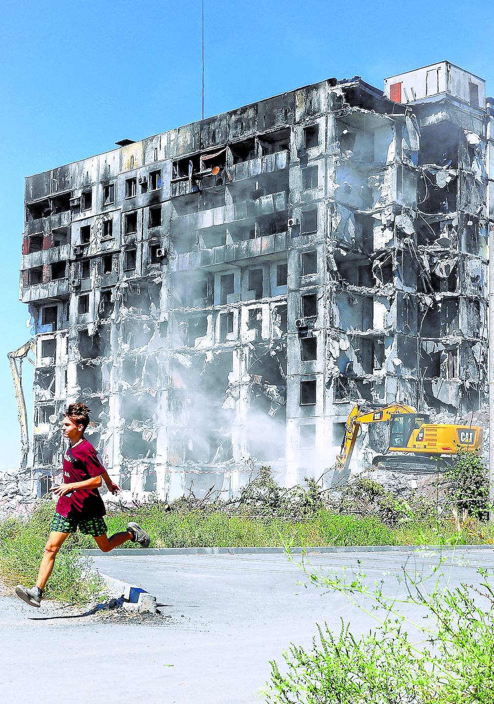 A teenager walks past a war-destroyed block of flats in Mariupol.