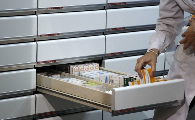 Un químico coloca medicamentos en un cajón en una farmacia en Madrid.
